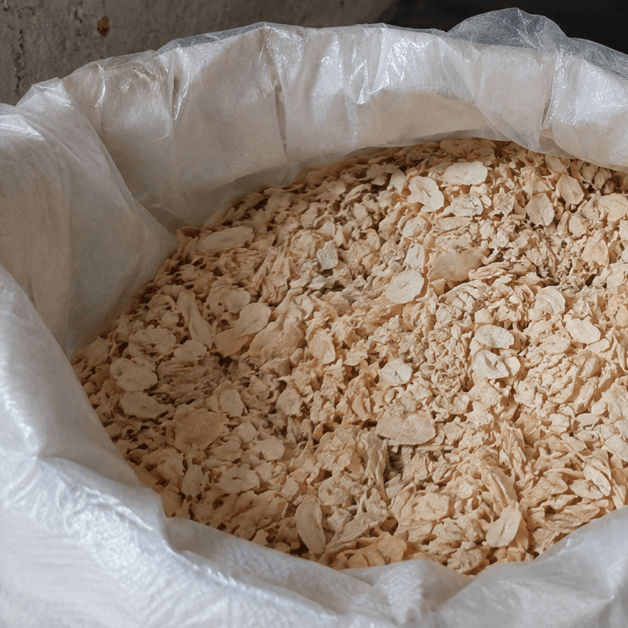 Dehydrated garlic flakes in an open woven sack with a food-grade liner